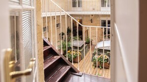 A wooden staircase leading to a balcony with a view of the courtyard. - Hôtel Churchill (Bordeaux)