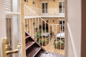 Una scala in legno conduce a un balcone con vista sul cortile.