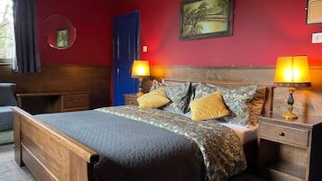 A neatly arranged bedroom with a bed, two bedside tables with lamps, a dresser, a blue door, and a framed picture on the wall.