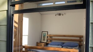 Una habitación con una cama de madera, una mesita de noche pequeña y un cuadro enmarcado en la pared.