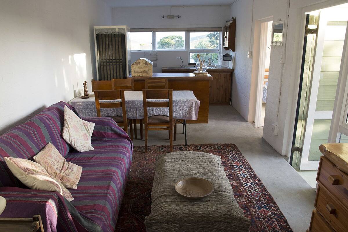 A cozy living room with a sofa, chairs, and a dining area with a table and chairs.