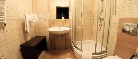 Un baño con lavamanos, inodoro y ducha con mampara de vidrio.