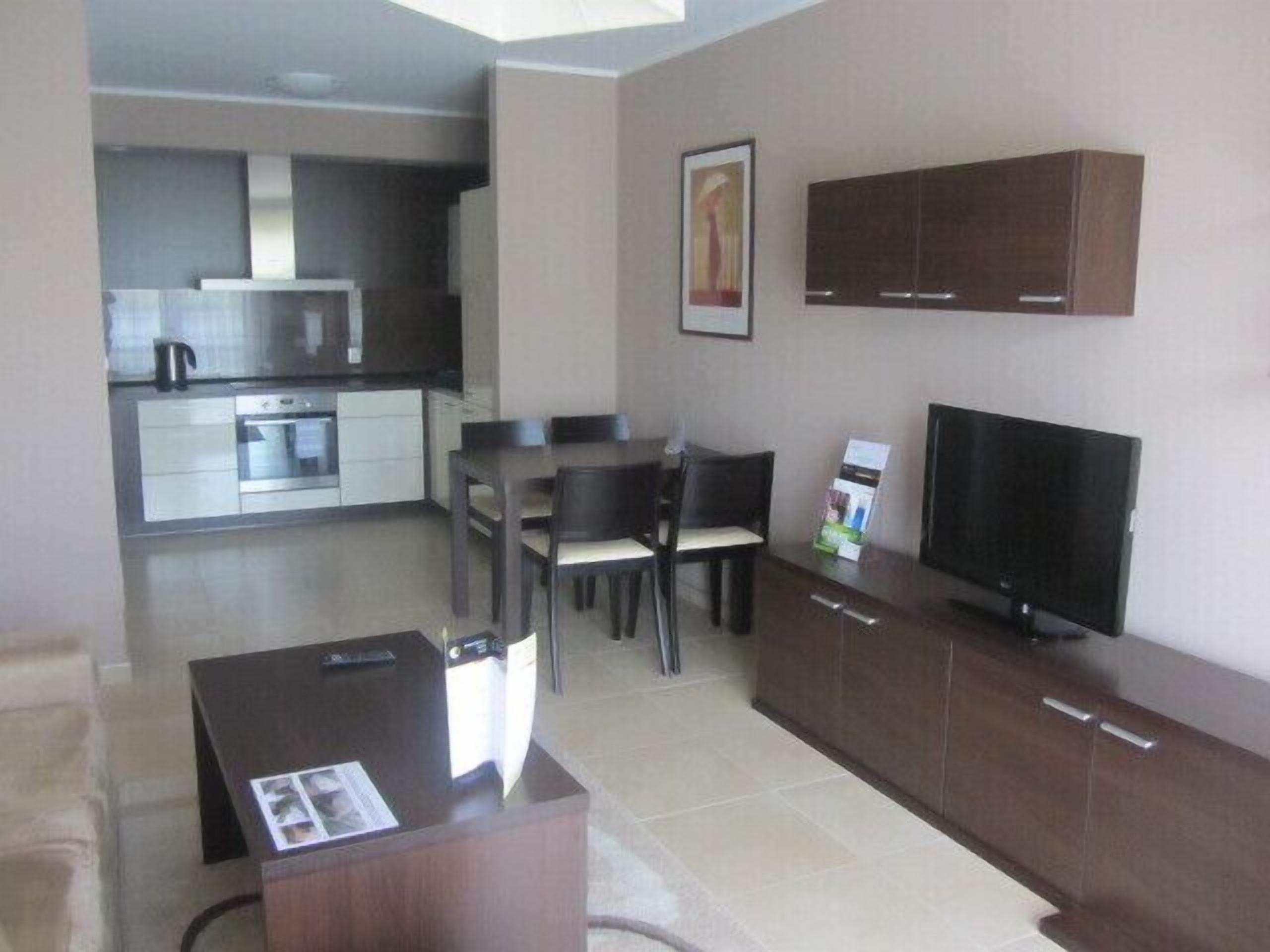 A compact living space with a kitchenette, dining area, and a TV.