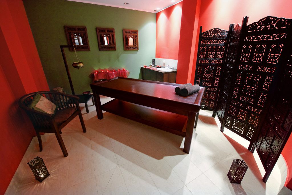 A room with a wooden table, a chair, a small cabinet, and a decorative partition.