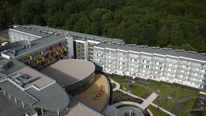 Een modern hotel met een terras op het dak, een ronde binnenplaats en een aangelegde tuin.