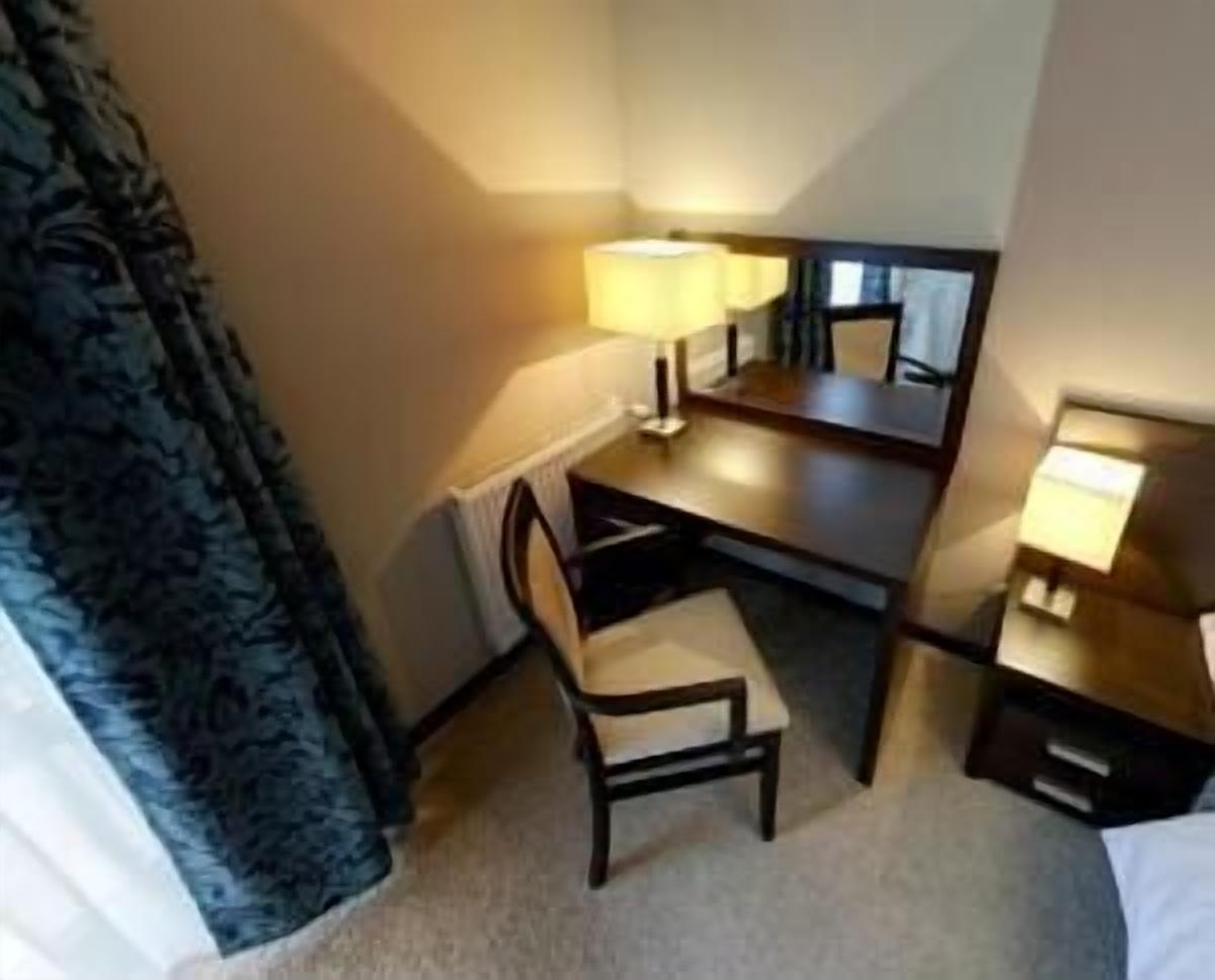 Habitación de hotel con escritorio, silla, dos lámparas de noche y un espejo grande.