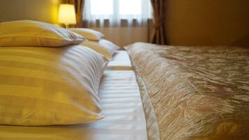 A hotel room with a bed featuring striped and textured bedding, a lamp, and a window with curtains.