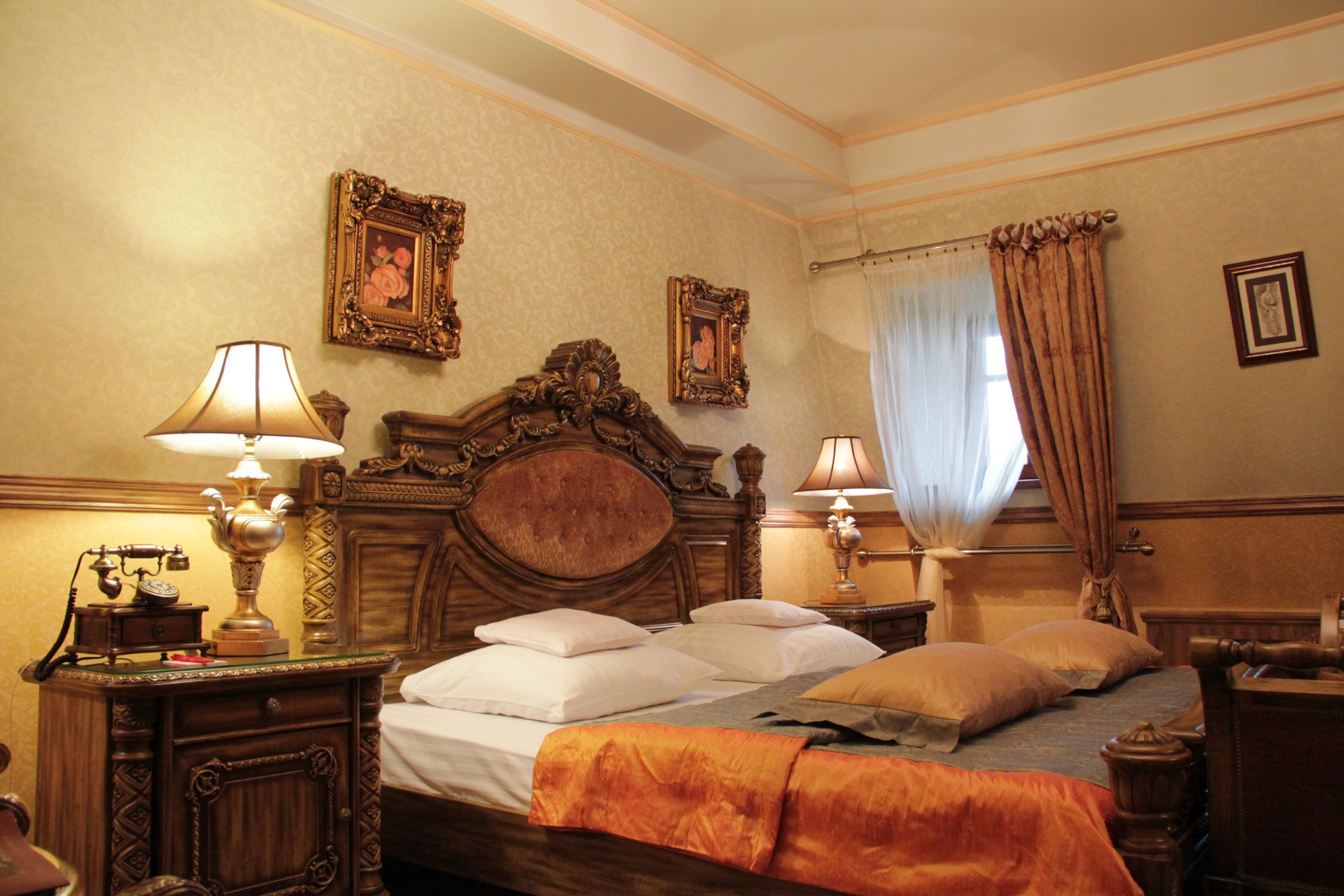 Habitación de hotel con una cama de madera, dos mesitas de noche con lámparas y una ventana con cortinas.