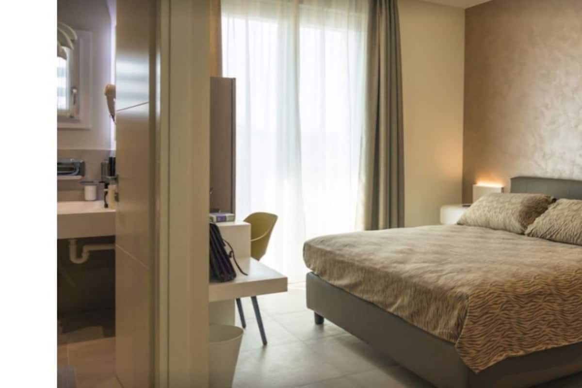 Een slaapkamer met een groot bed, nachtkastjes en een raam met gordijnen.