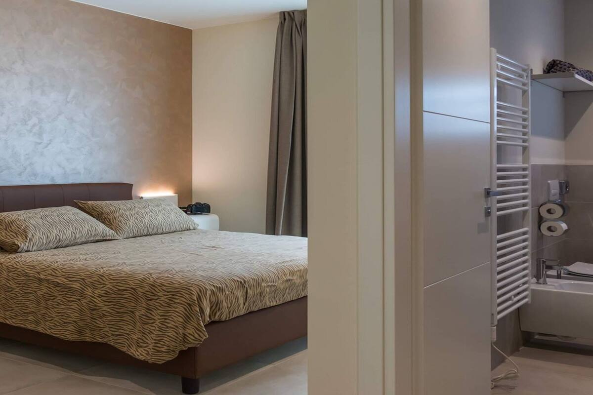 Een moderne slaapkamer met een groot bed, nachtlampjes en een badkamer met toilet en bidet.