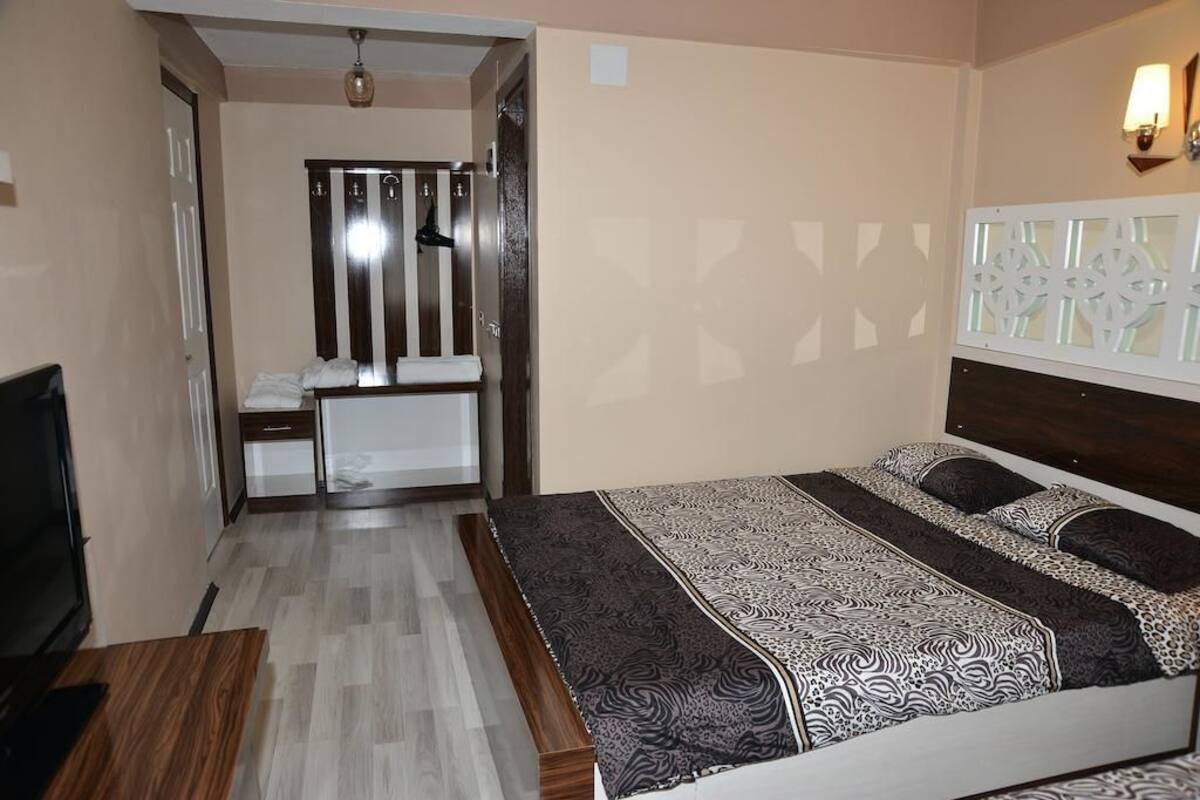 A bedroom with a bed, a TV, a desk, and a wardrobe.