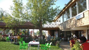 Un espace extérieur aménagé avec des tables et des chaises, une partie abritée et un bâtiment portant l’inscription « Hôtel ».