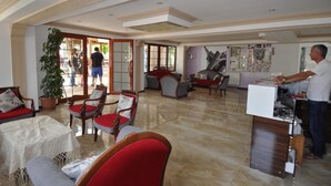 Un vaste espace de vie comprenant un grand espace cuisine ouvert, un coin repas avec des chaises rouges et grises, et une vue sur une terrasse extérieure accessible par une porte vitrée.