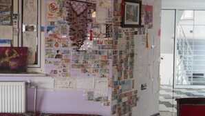 Une pièce dont un mur est recouvert de divers objets, notamment des billets de banque, des photographies et un tableau encadré.