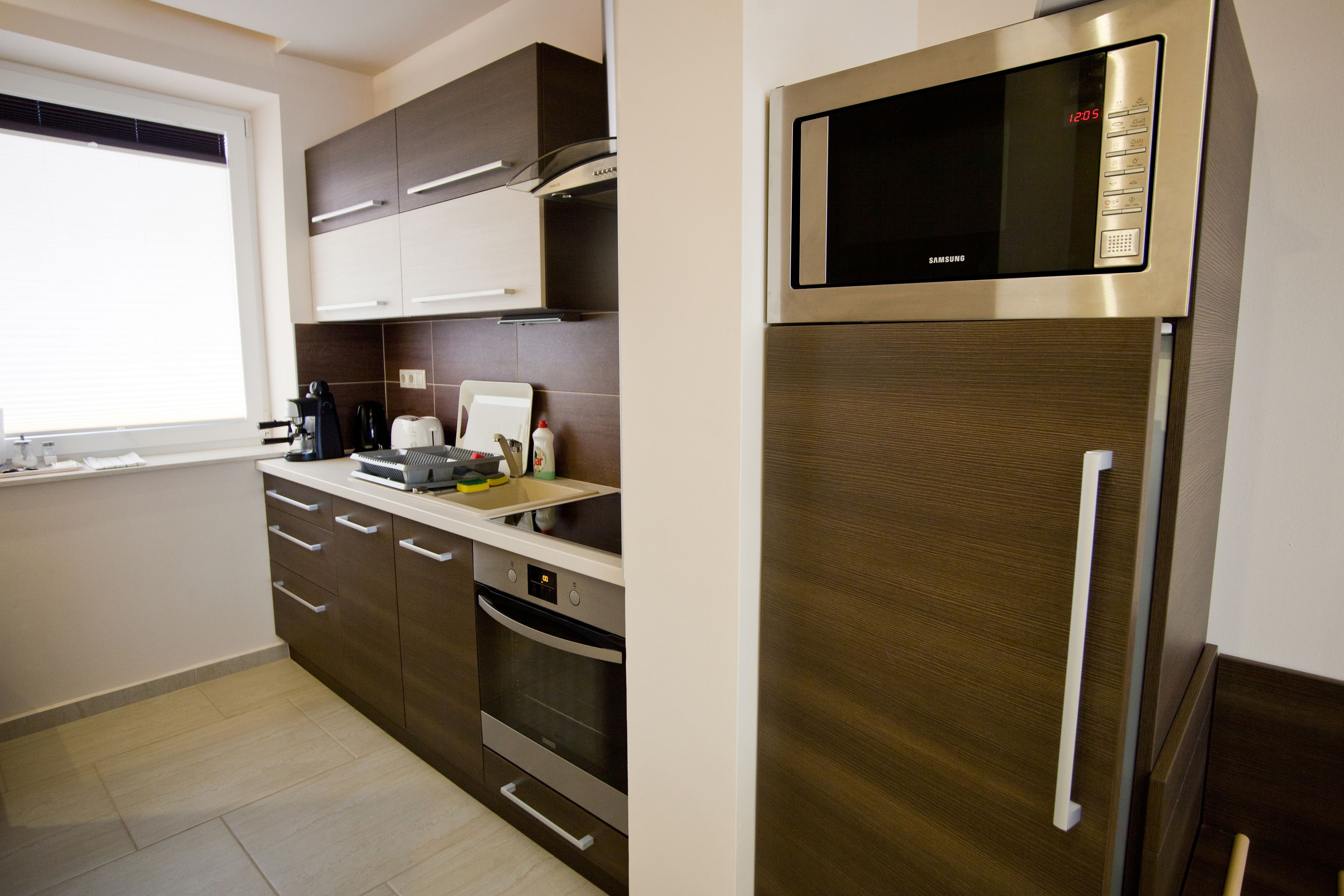 Eine moderne Küche mit Edelstahlgeräten, darunter eine Mikrowelle und ein Backofen, sowie einem integrierten Geschirrspüler.