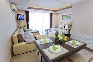 Een moderne hotelkamer met een zithoek, een bank, een bed en een aan de muur bevestigde televisie.