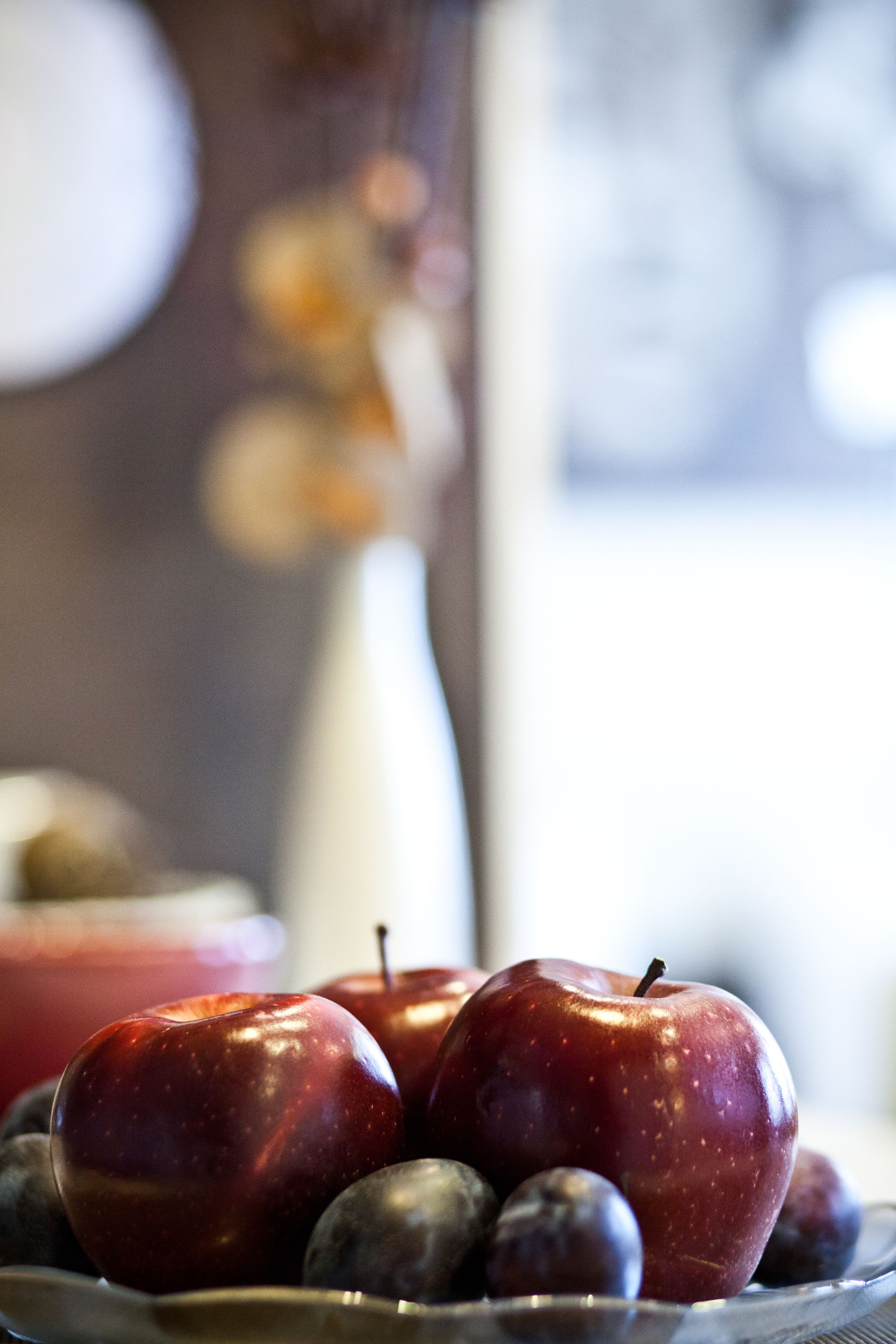 Primer plano de un frutero con manzanas y ciruelas.
