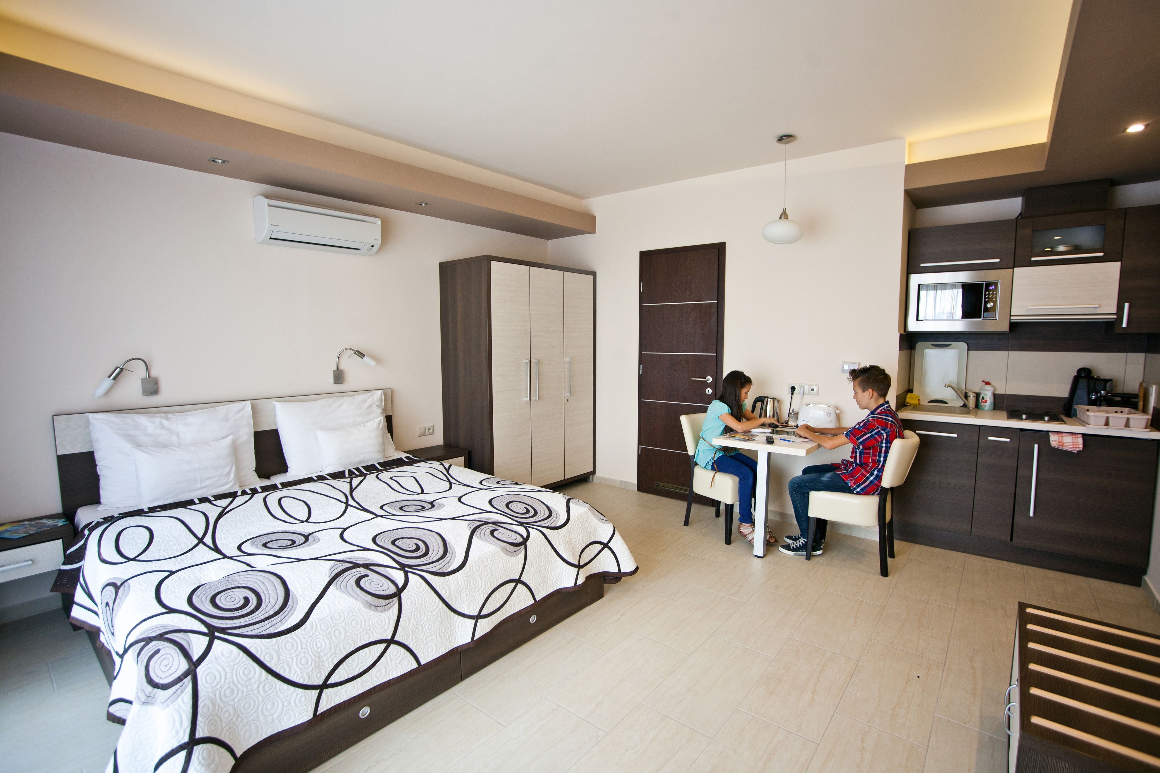 Une chambre d’hôtel moderne dotée d’un grand lit, d’un coin repas et d’une kitchenette.