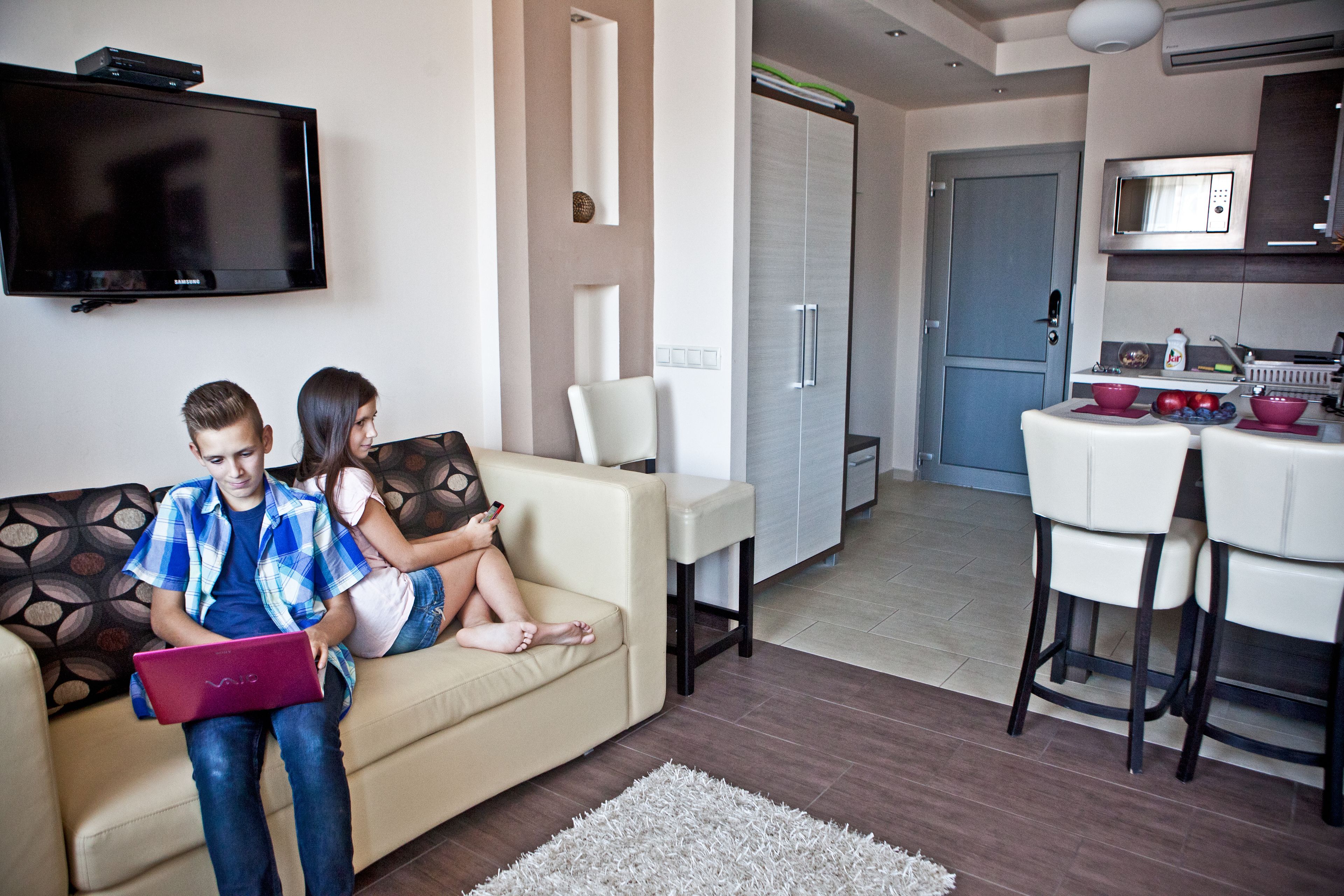 Ein modernes Wohnzimmer mit Sofa, Fernseher und Essbereich mit Stühlen und Tisch.
