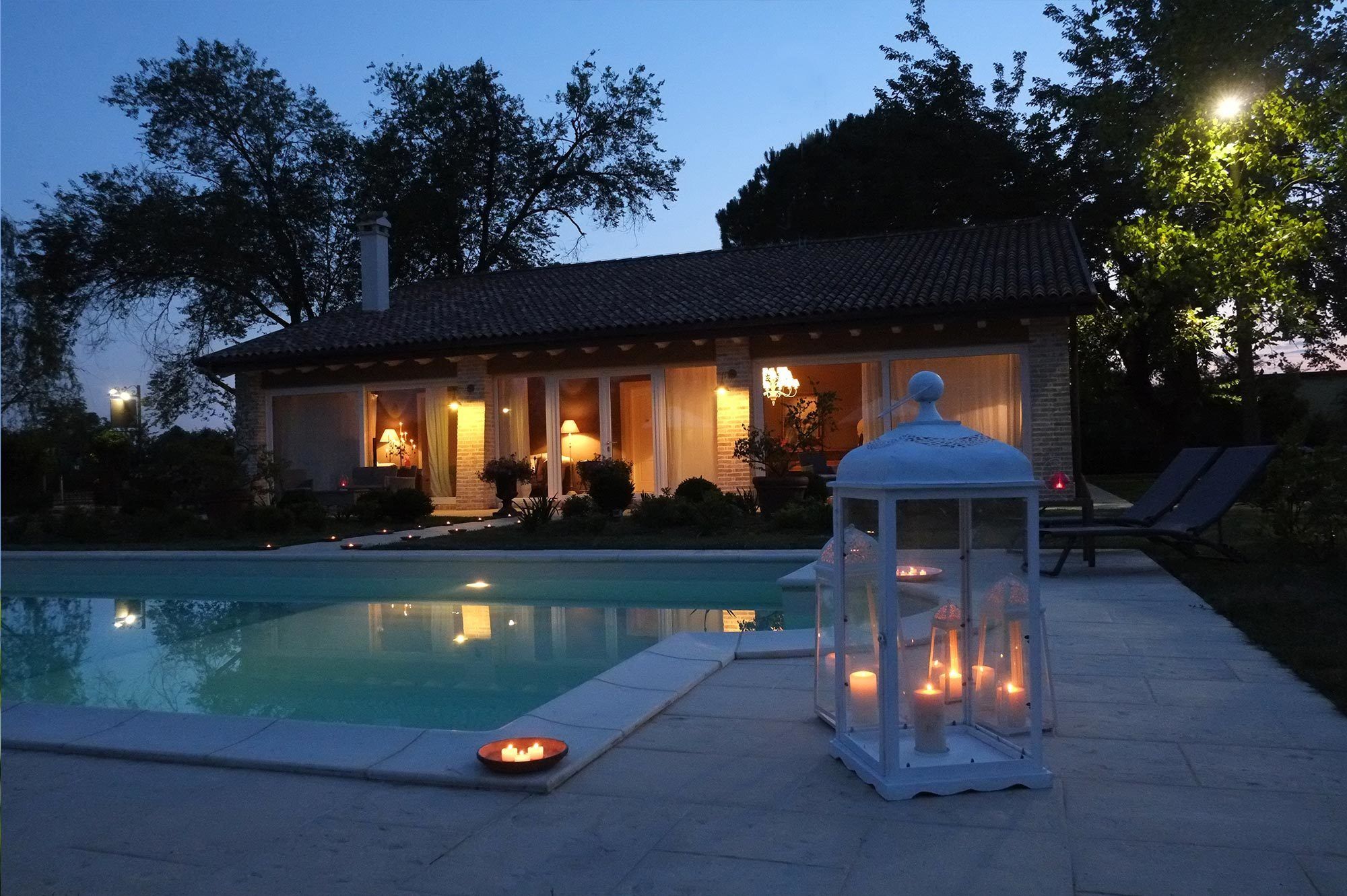 Zona piscina con una casa sullo sfondo, un lanterne e una piccola piscina.