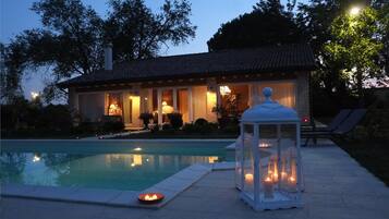 Zona piscina con una casa sullo sfondo, un lanterne e una piccola piscina.