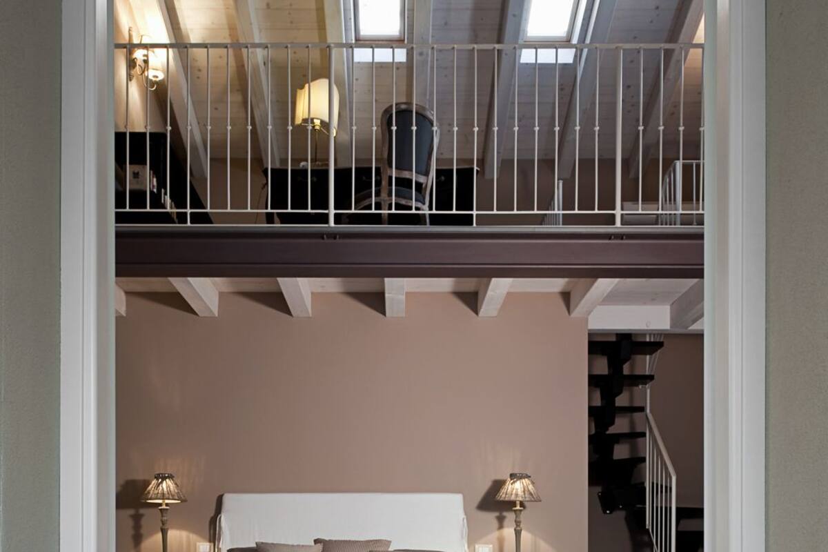 A bedroom with a loft area above the bed, featuring a staircase and skylights.