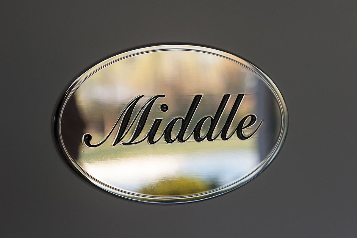A circular metallic sign with the word "Middle" engraved on it.