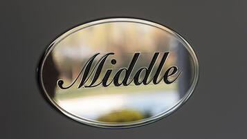 A circular metallic sign with the word "Middle" engraved on it.