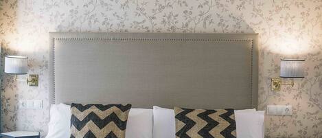 Une chambre d’hôtel avec un grand lit, deux tables de chevet et un papier peint à motifs floraux.