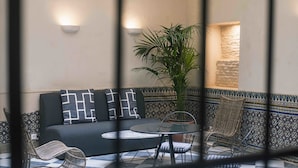 Een gezellige zithoek met een bank, twee stoelen, een klein tafeltje en een plant in pot.