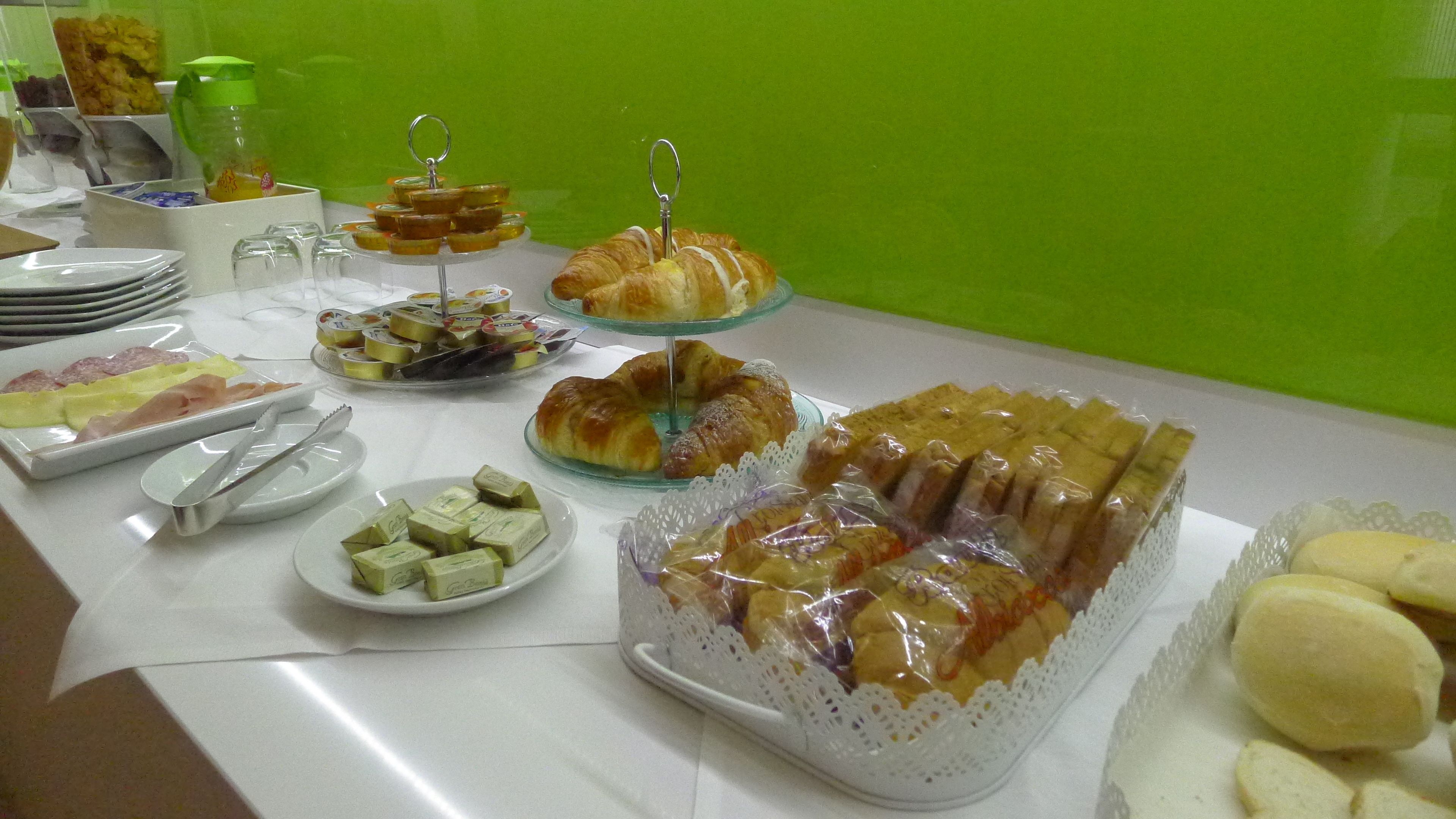 A buffet table with various food items including pastries, sandwiches, and fruit.