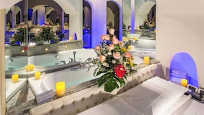 A luxurious bathroom with a large mirror, a bathtub, and a floral arrangement. - Motel K (Casei Gerola)