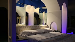 A bedroom with a large bed, a vanity with a mirror, and a unique arched ceiling design. - Motel K (Casei Gerola)