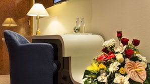 A hotel room with a desk, a lamp, a bouquet of flowers, and a bottle of water. - Motel K (Casei Gerola)