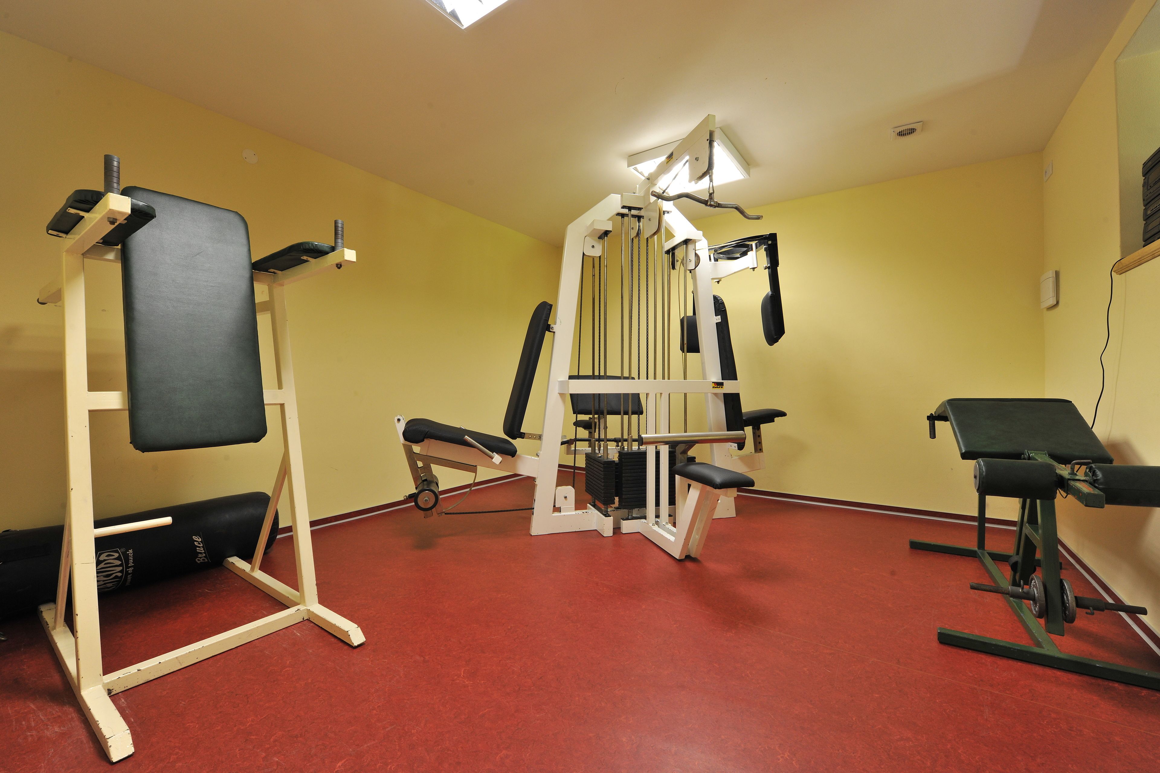 A gym with exercise equipment, a red floor, and yellow walls.