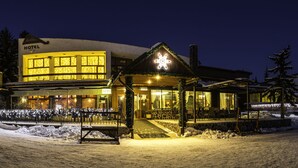 Un hotel con una entrada cubierta de nieve y un letrero iluminado.