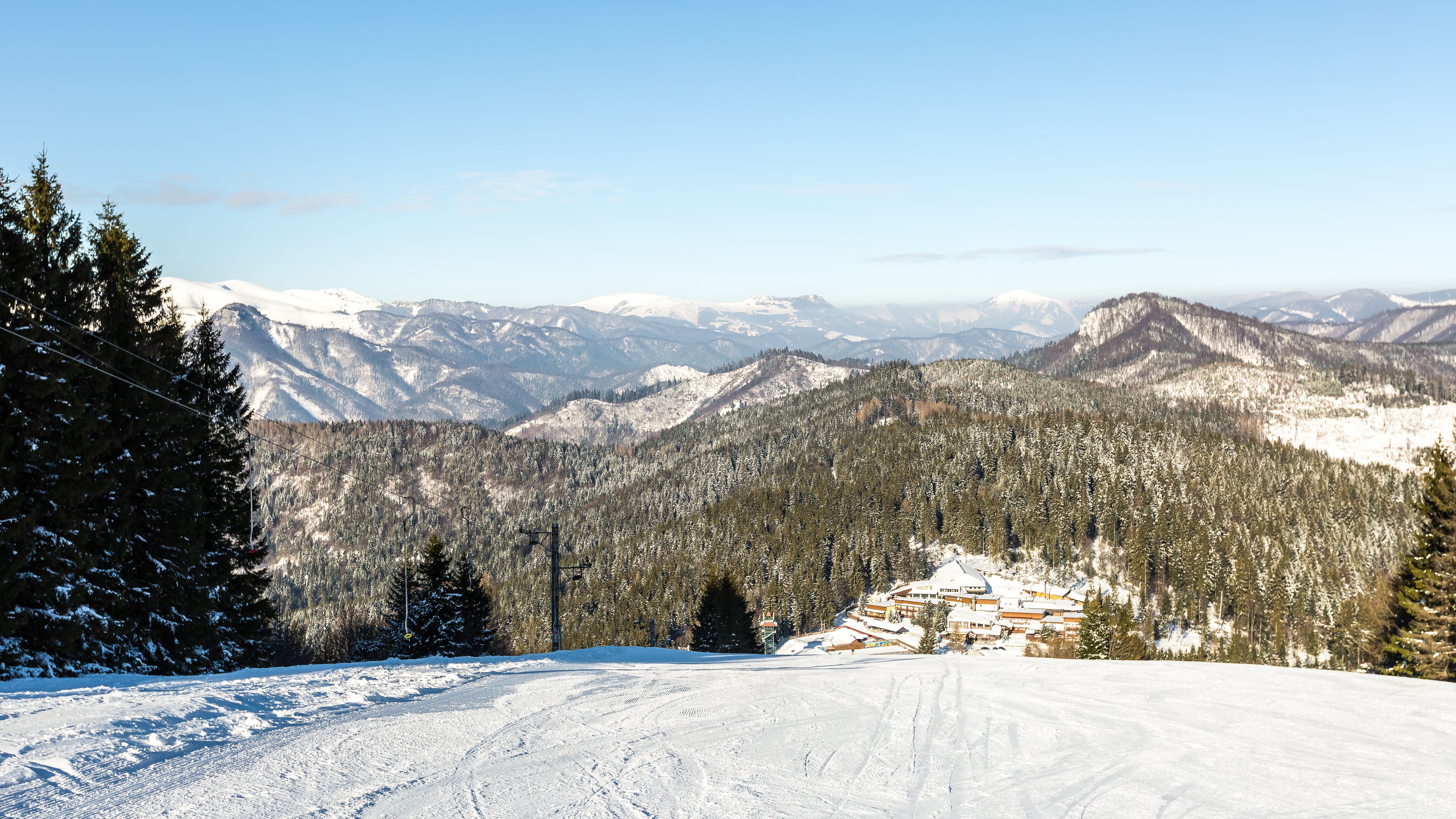 A snowy mountain landscape with a ski resort in the foreground.