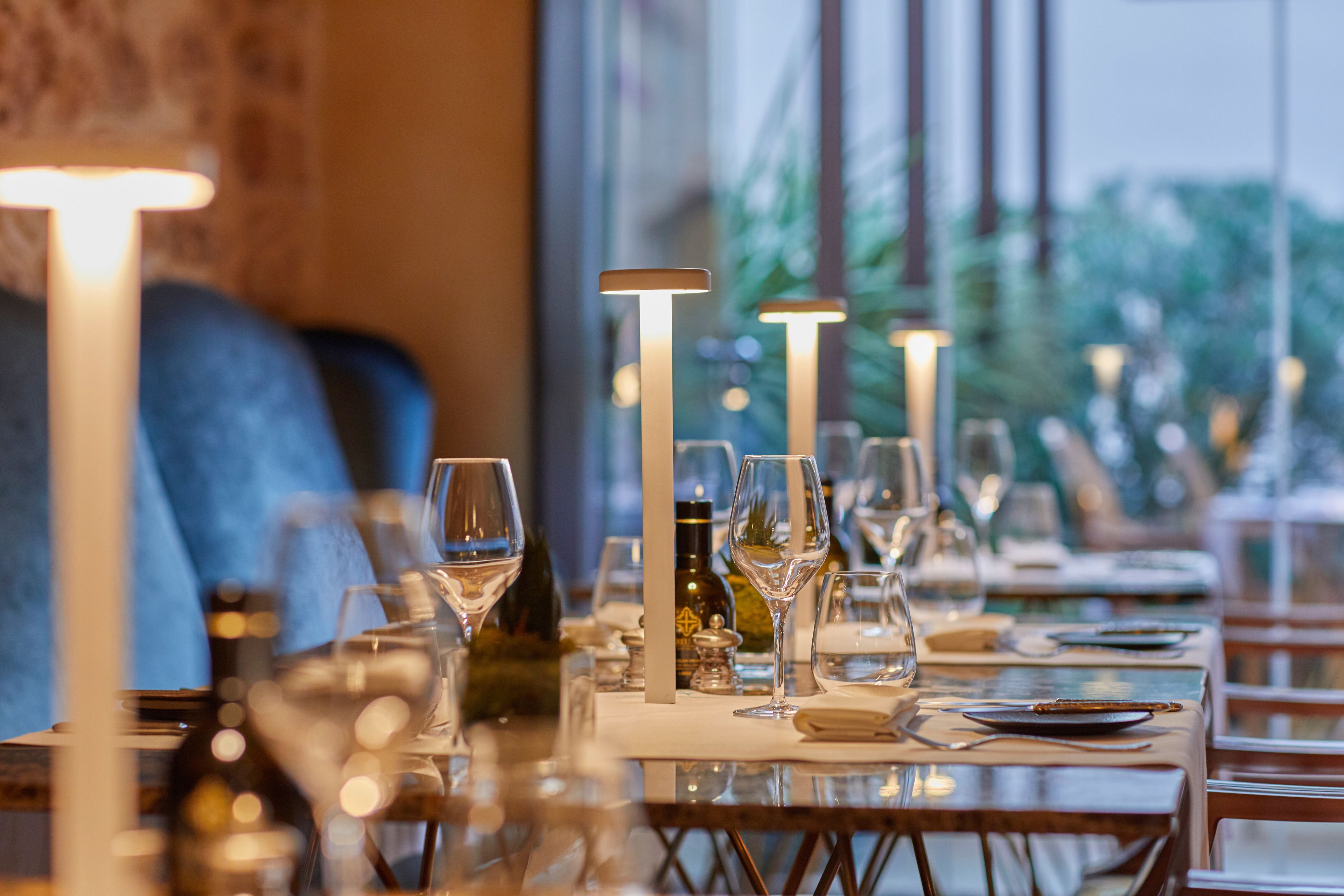 A restaurant interior with tables set for dining, wine glasses, and candles.