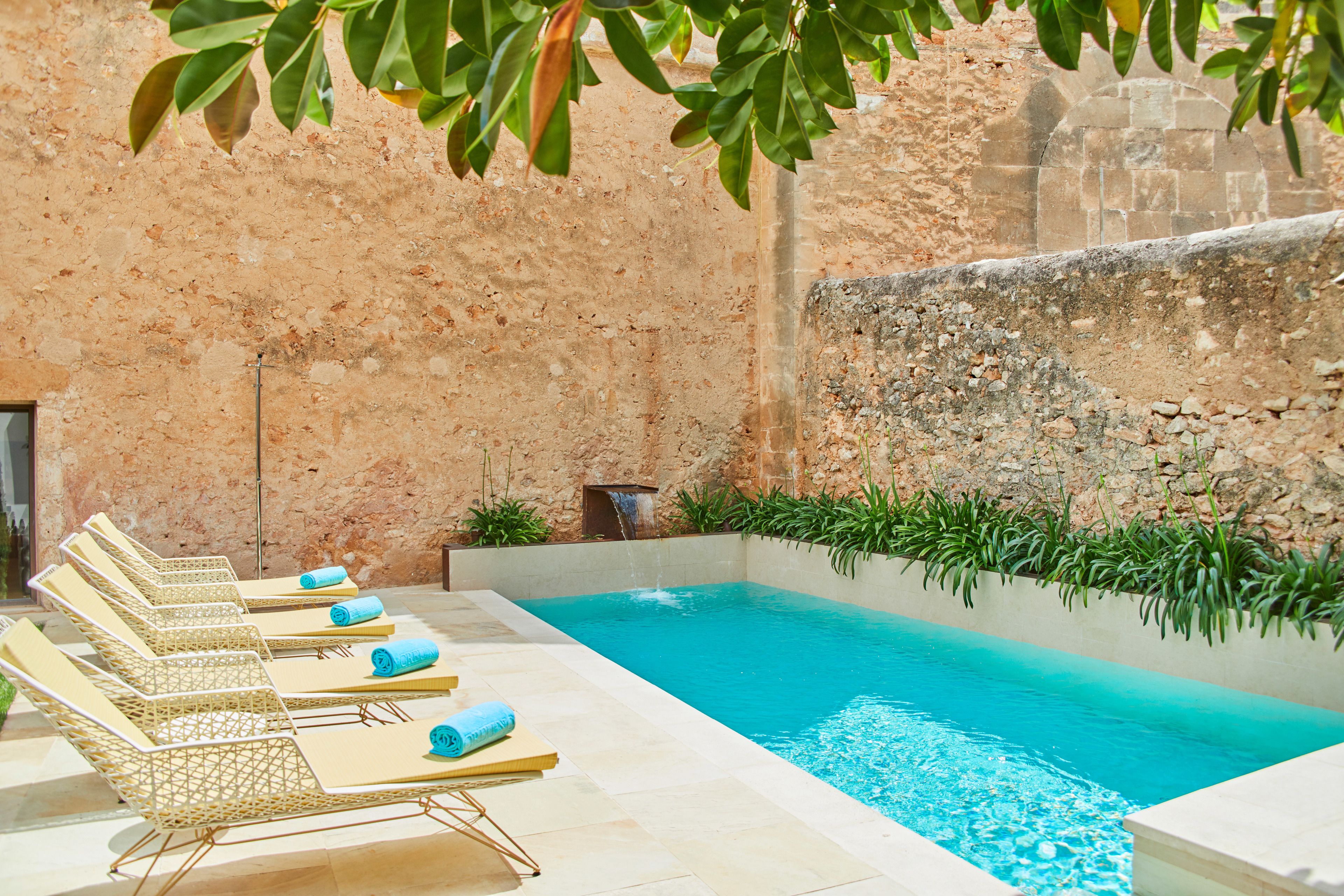 A poolside area with lounge chairs and a small waterfall feature.