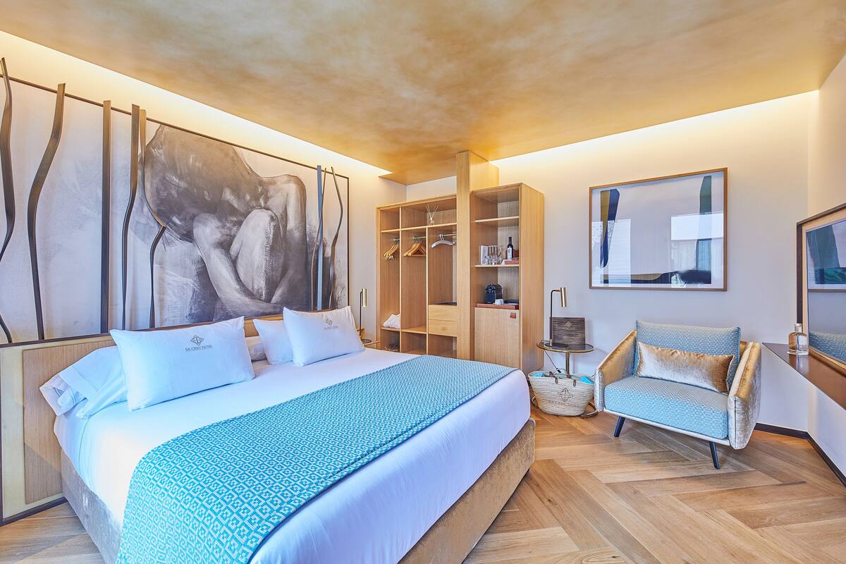 Une chambre d’hôtel moderne dotée d’un grand lit, d’une armoire, d’un coin salon et d’œuvres d’art accrochées aux murs.