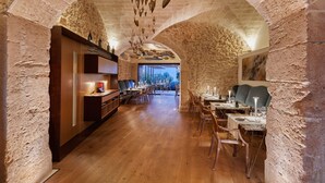 Un interior con un arco de piedra, suelo de madera y mesas dispuestas para comer.