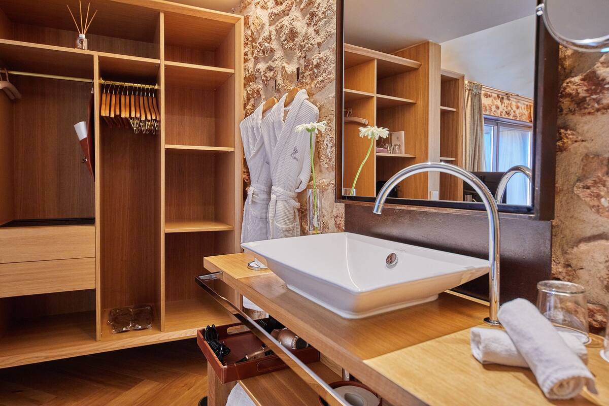 Une salle de bain moderne avec un grand miroir, un meuble-lavabo en bois et des étagères intégrées.
