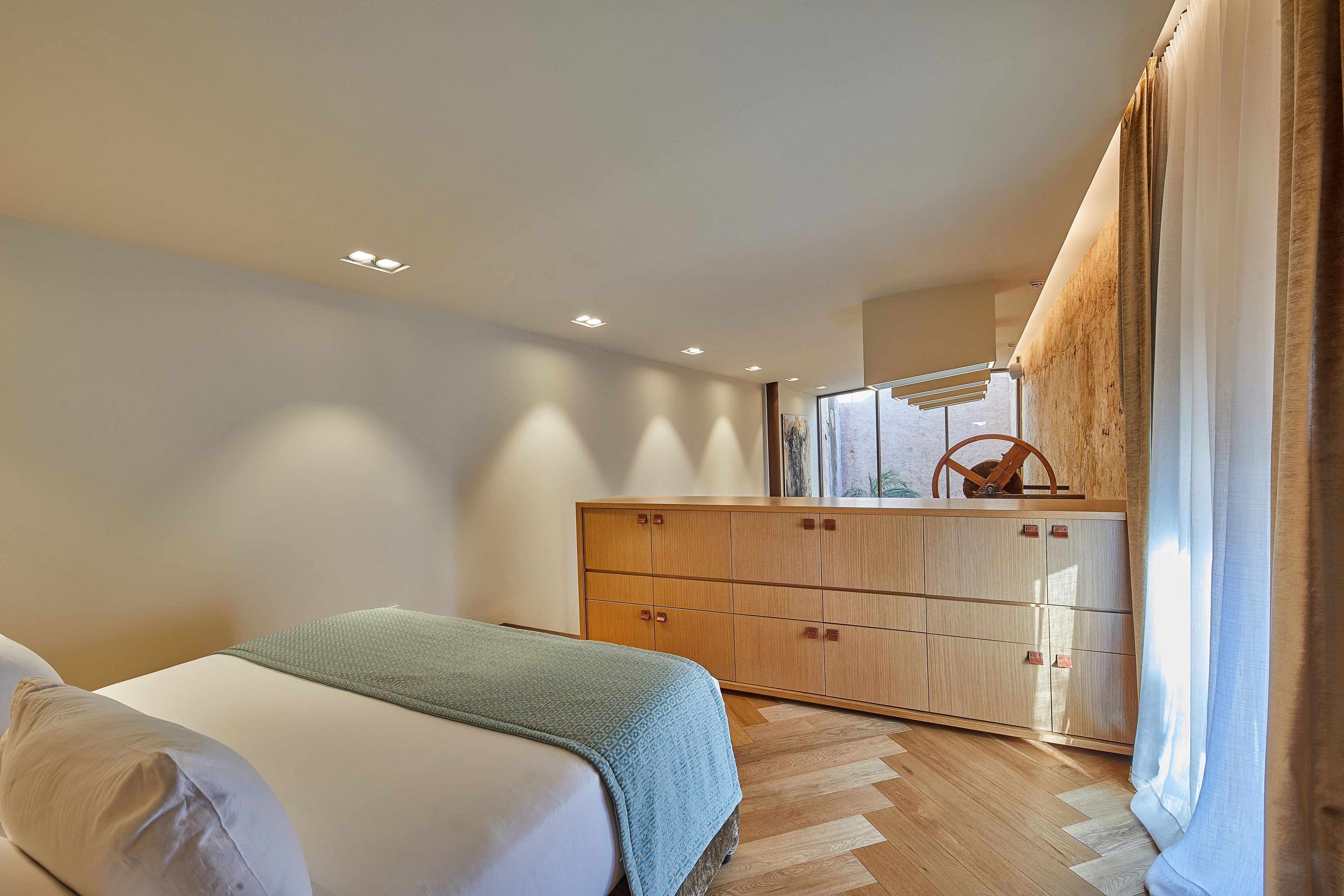 Quarto com cama, guarda-roupa de madeira e janela com cortinas.