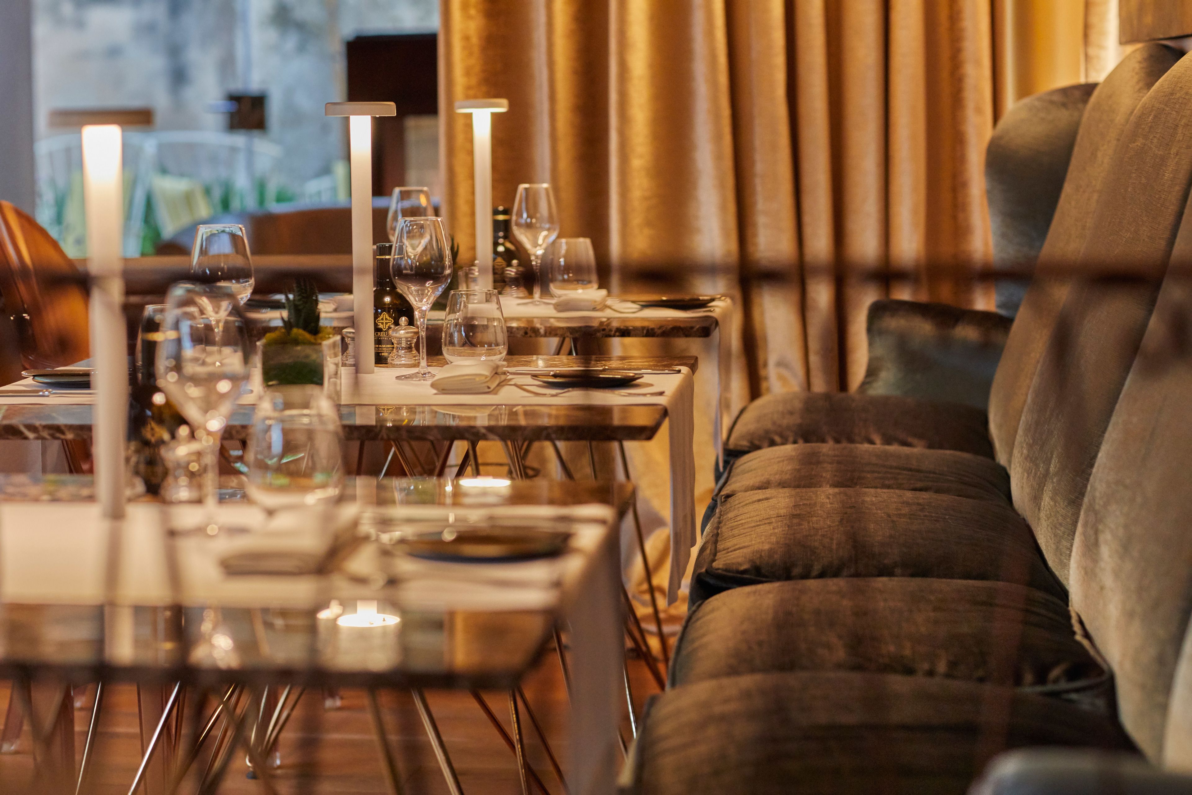 A dining area with tables set for a meal, featuring clear glassware and candles.