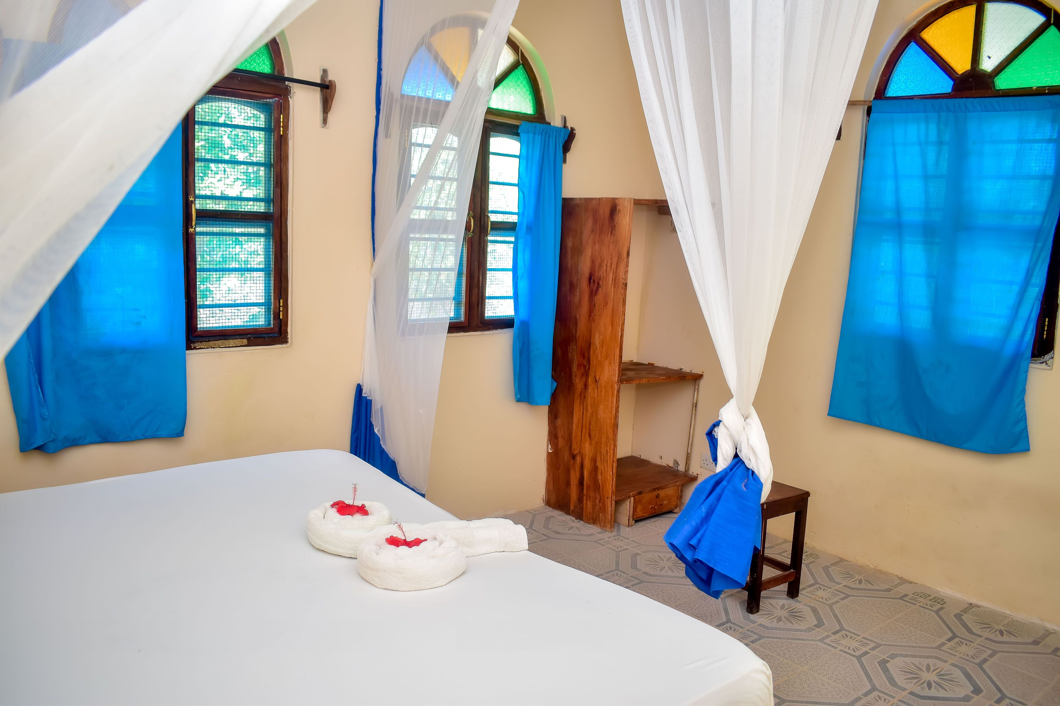 Una habitación con una cama, un armario de madera y una ventana con cortinas azules.