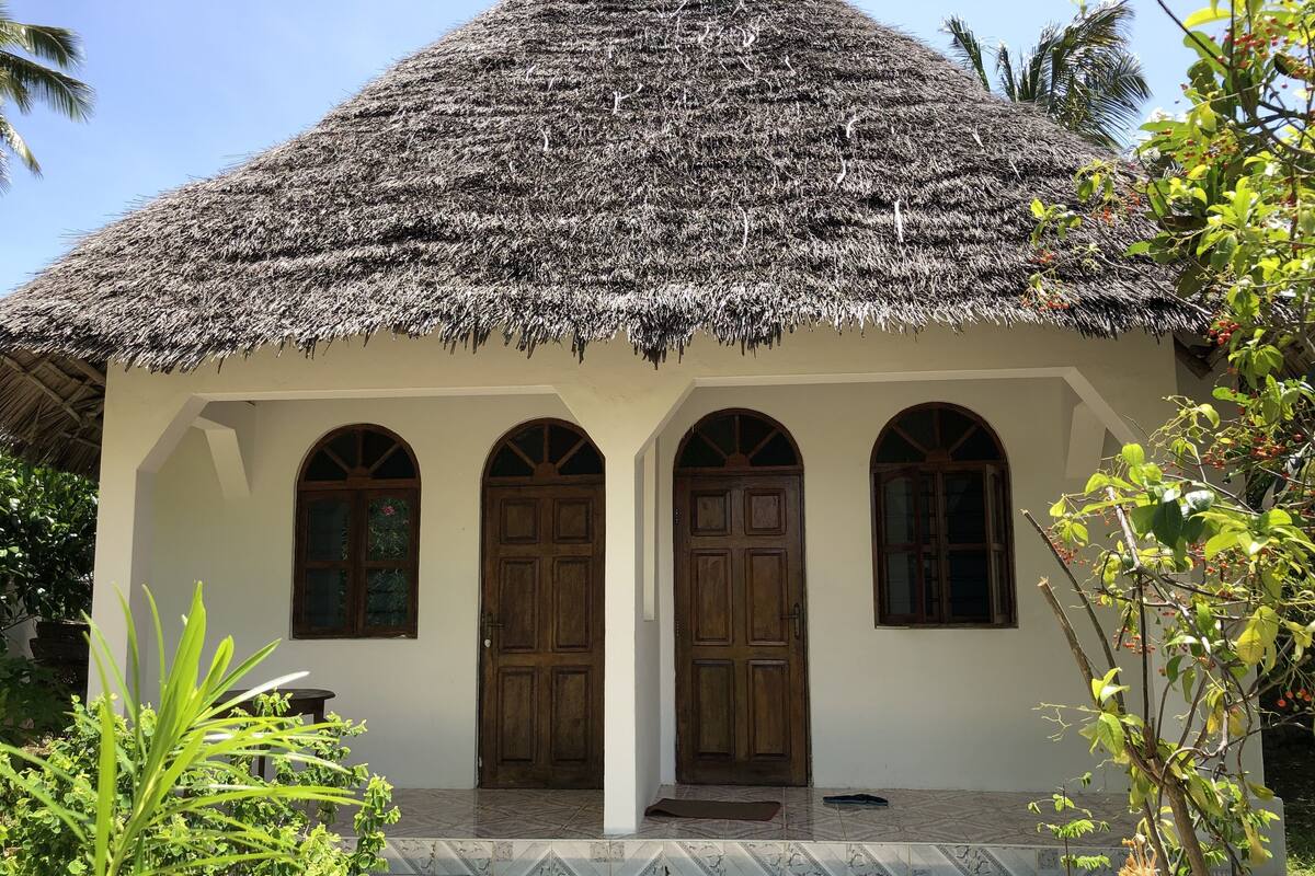 Una casa tradicional con techo de paja, ventanas de arco y entrada con azulejos.
