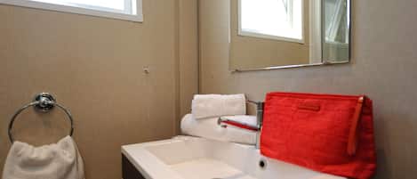 A bathroom with a white sink, a mirror, and a towel rack.