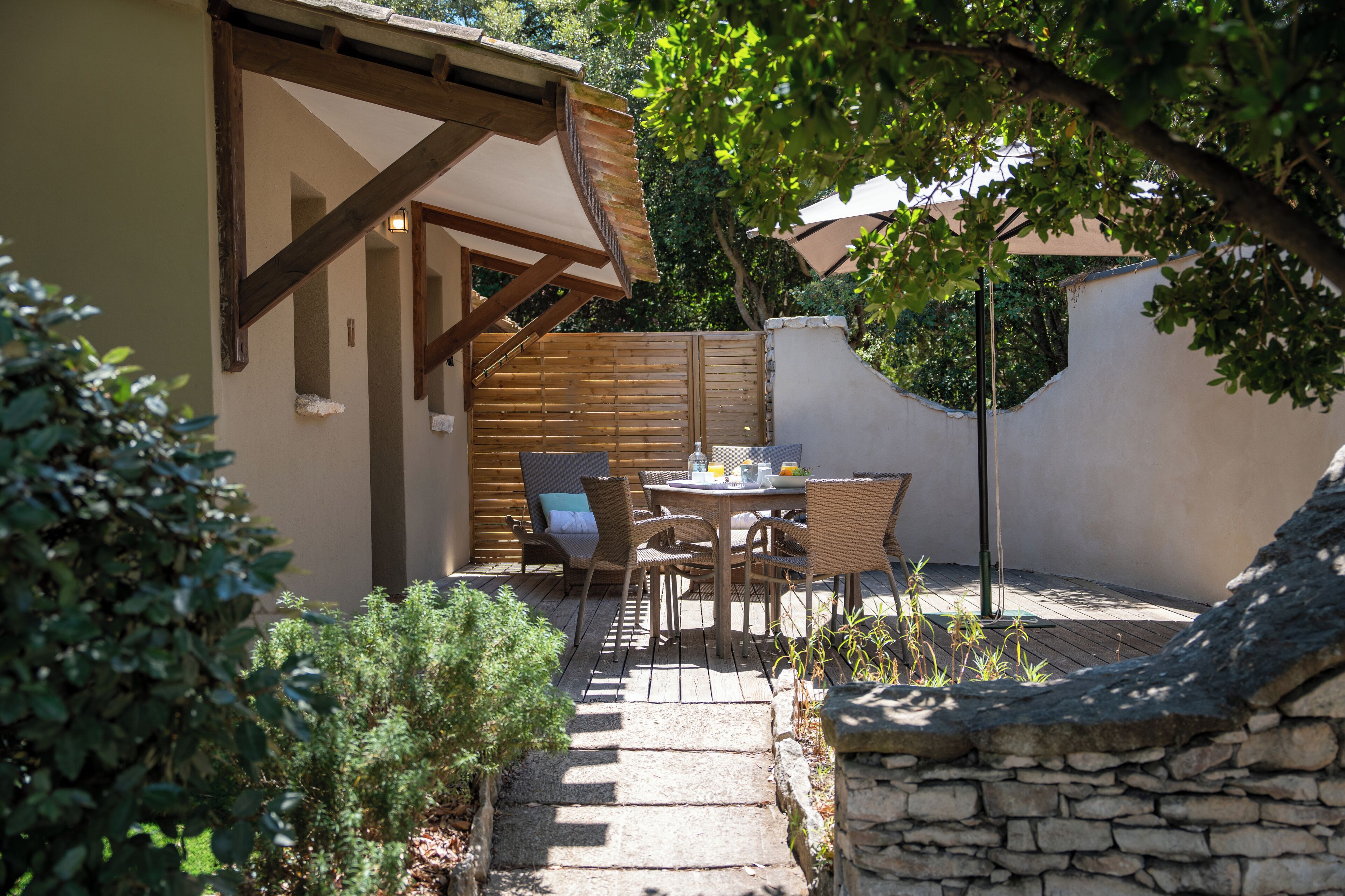 A patio with a table and chairs, a stone wall, and a wooden fence.