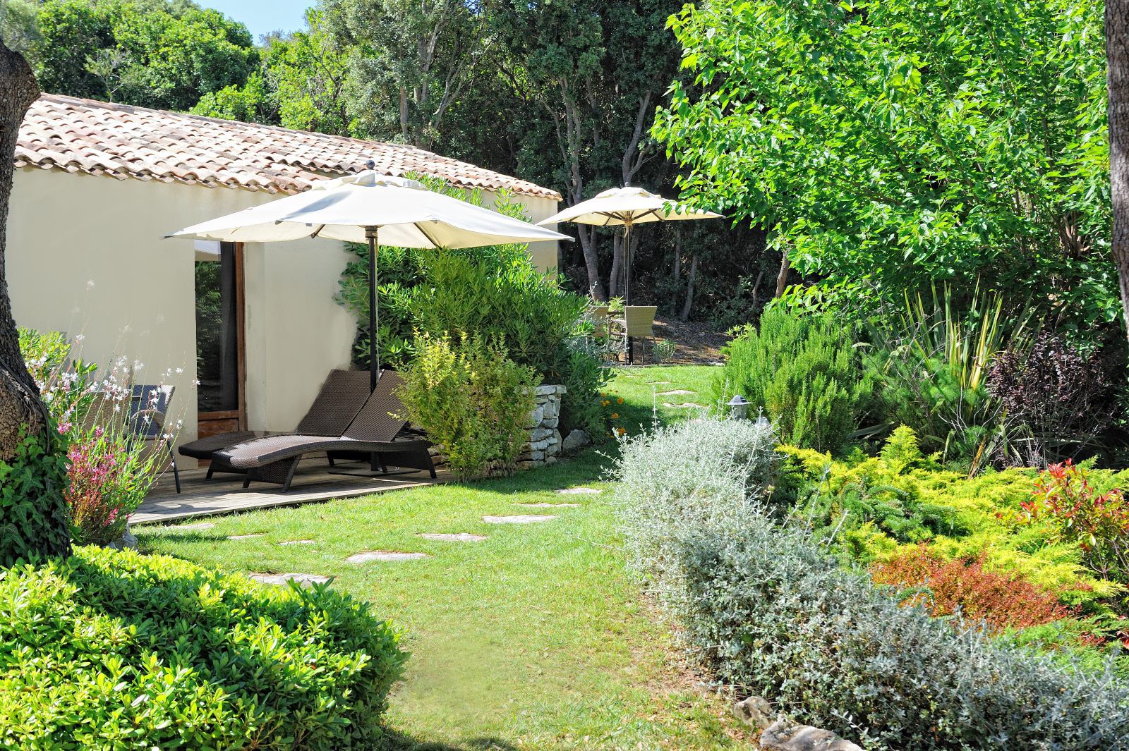 A garden with a patio, outdoor seating, and a building with a tiled roof.