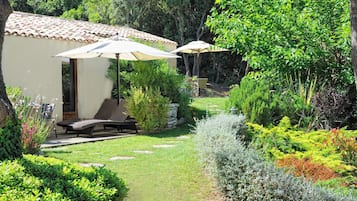 A garden with a patio, outdoor seating, and a building with a tiled roof.